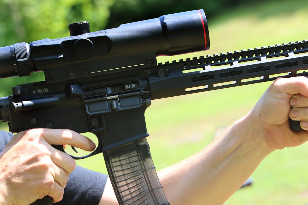 A person holds a rifle with a scope.